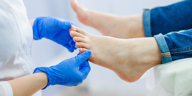 hands gently touching feet with a background of pink flowers highlighting beauty and selfcare for 11 toes and fingers