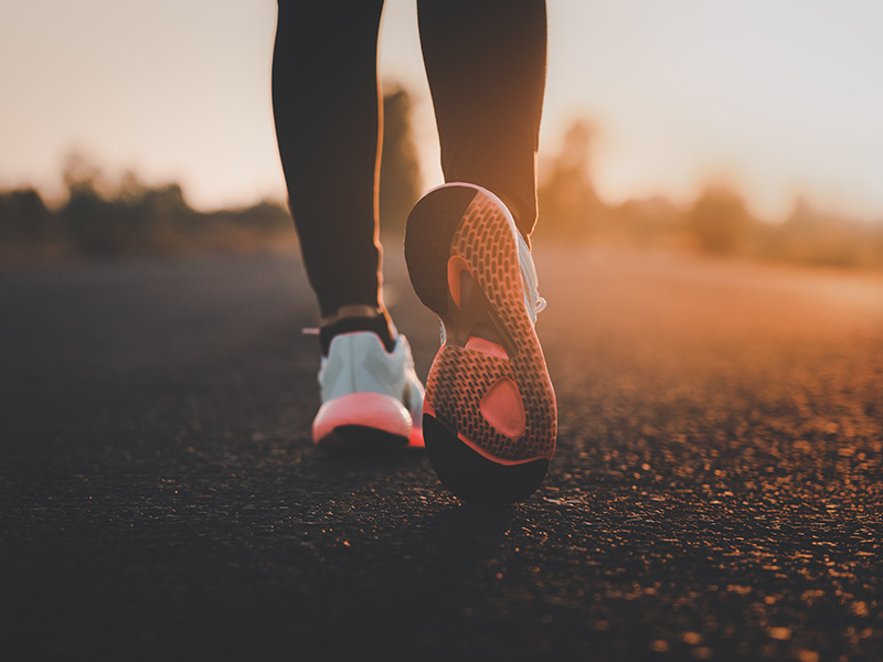 person walking on a road wearing athletic shoes at sunset with focus on the footwear featuring twelve unique design elements